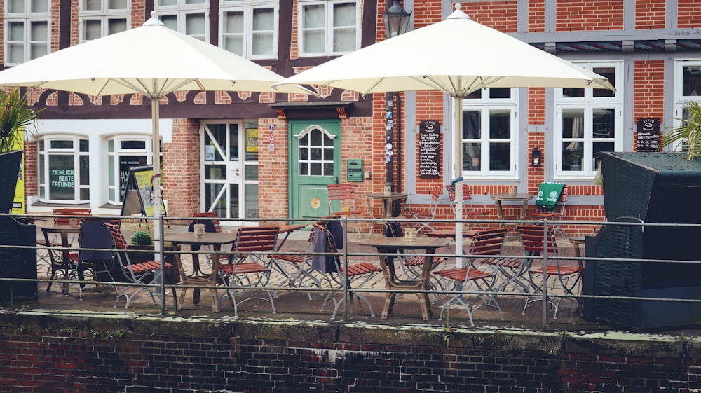 a group of tables with umbrellas outside of a building