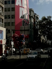 A happy gig worker standing next to their car wrapped with a colorful advertisement in a busy city street.