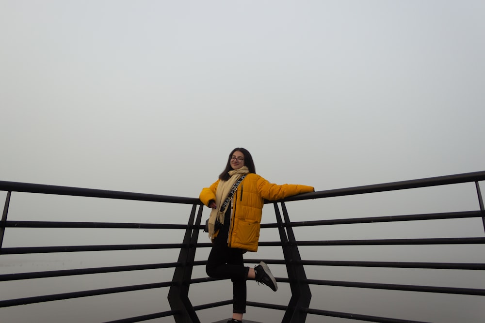 a woman in a yellow jacket standing on a bridge