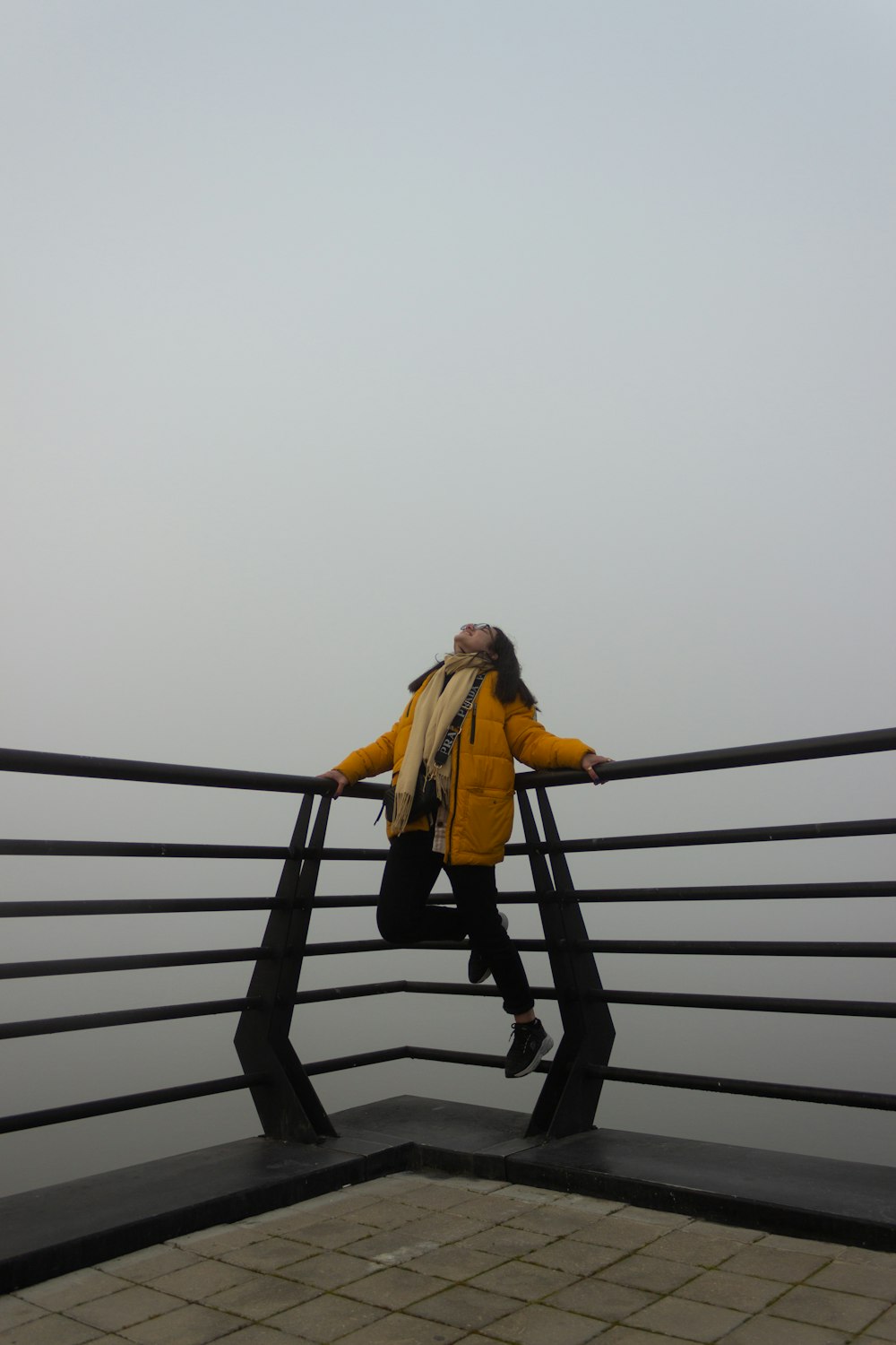 Une femme en veste jaune se tient debout sur une balustrade