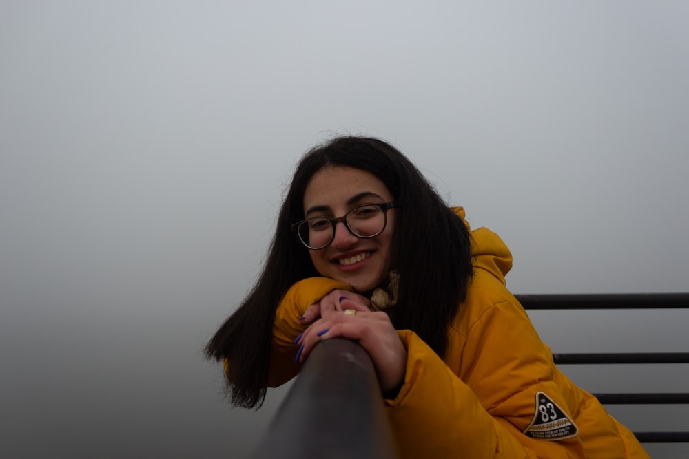 Une femme en veste jaune assise sur un banc