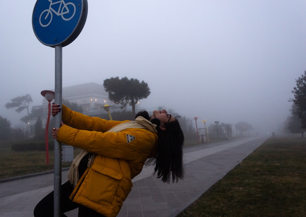 a woman leaning up against a street sign