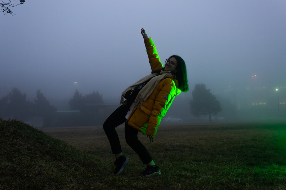 a woman in a yellow jacket is flying a kite