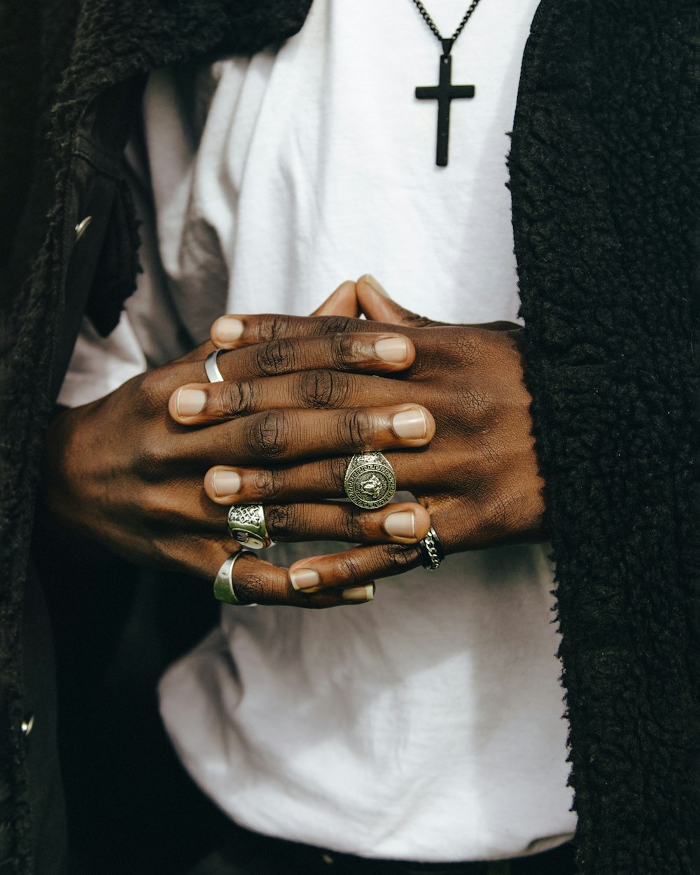 a person wearing rings and a cross necklace