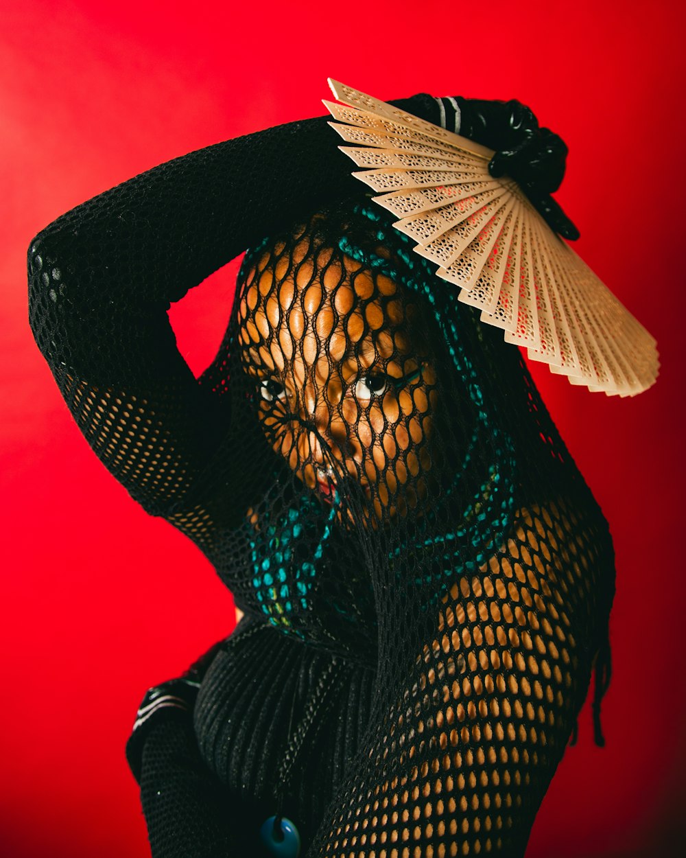 a woman in a fishnet top and a fan on her head