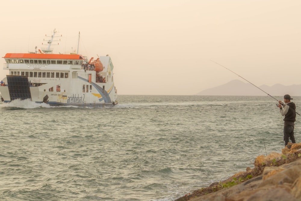 a man standing on a rock next to a large boat