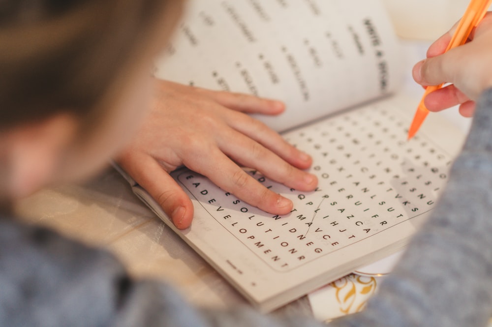 a child is writing on a book with a pencil