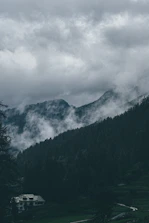 a house in the middle of a field with mountains in the background