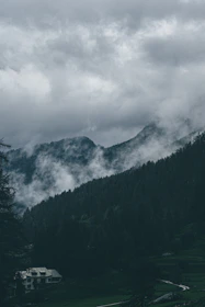 a house in the middle of a field with mountains in the background