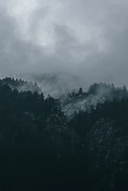a black and white photo of a mountain covered in clouds