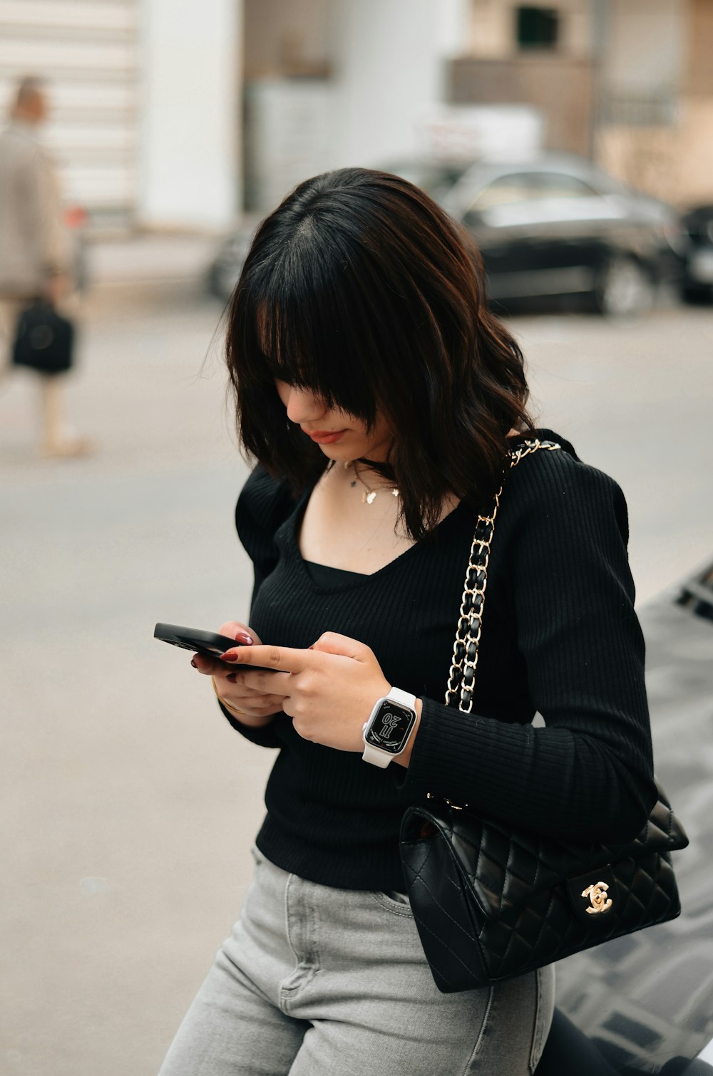 a woman in a black top is looking at her cell phone