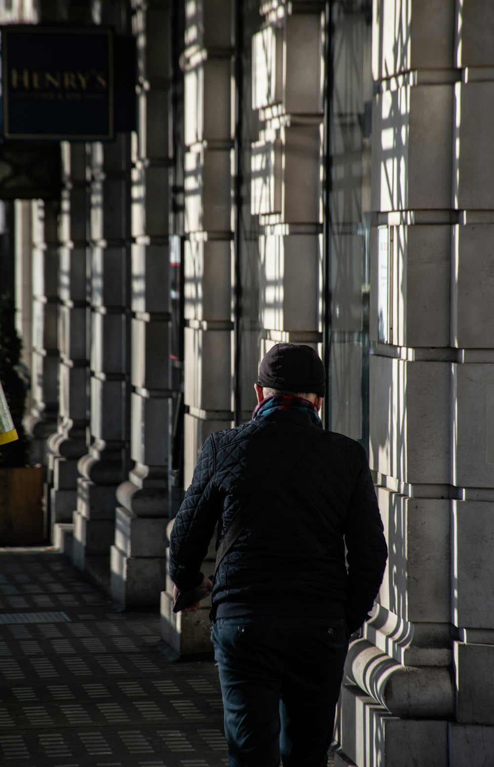 a man walking down a sidewalk next to a tall building