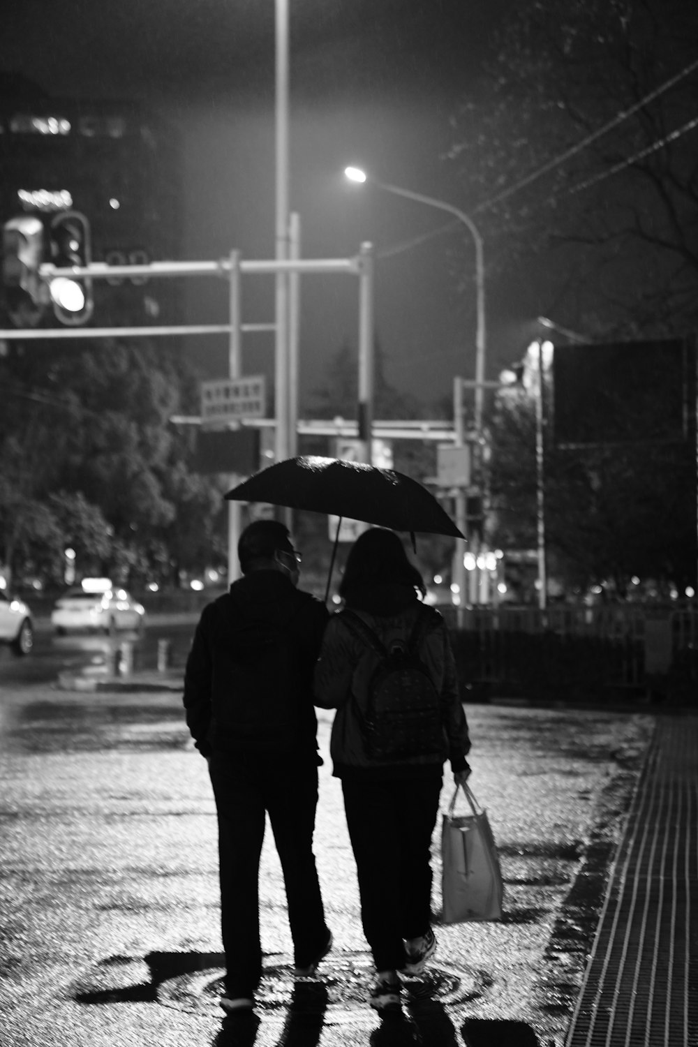 a couple of people walking down a street holding an umbrella