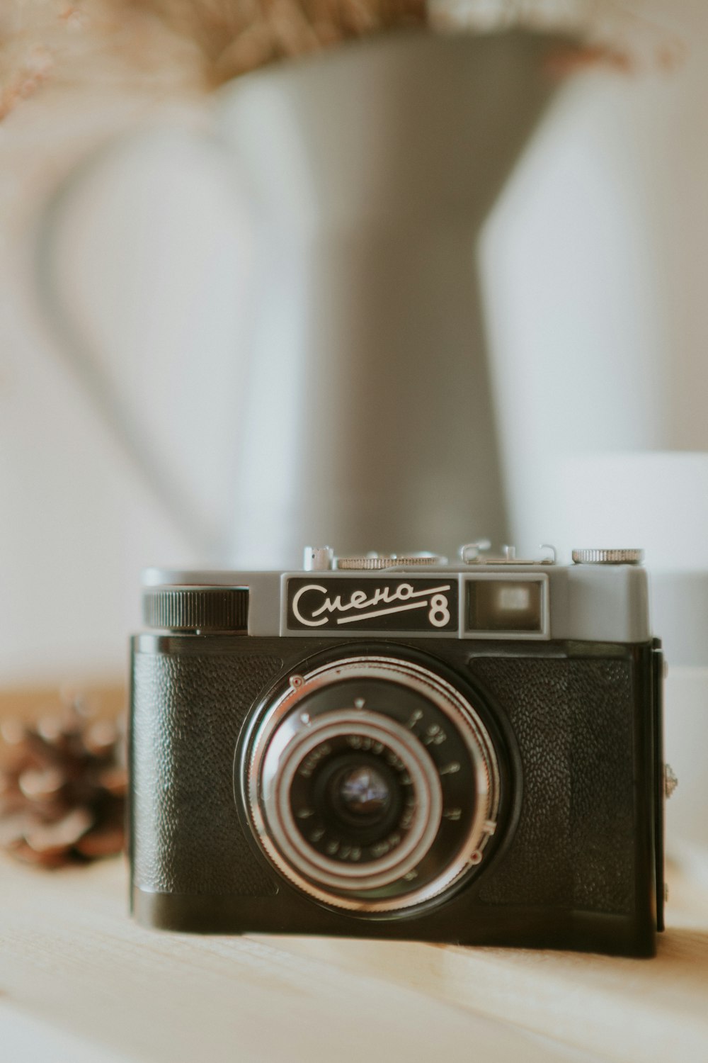 a camera sitting on top of a table next to a vase