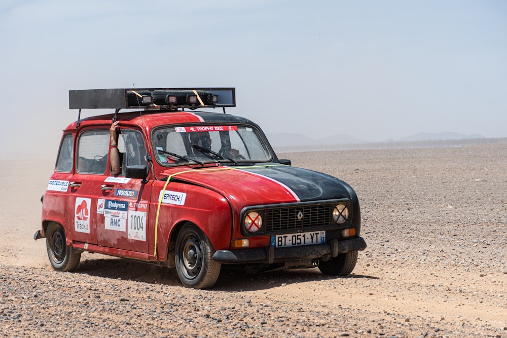 a small red car with a surfboard on top of it's roof