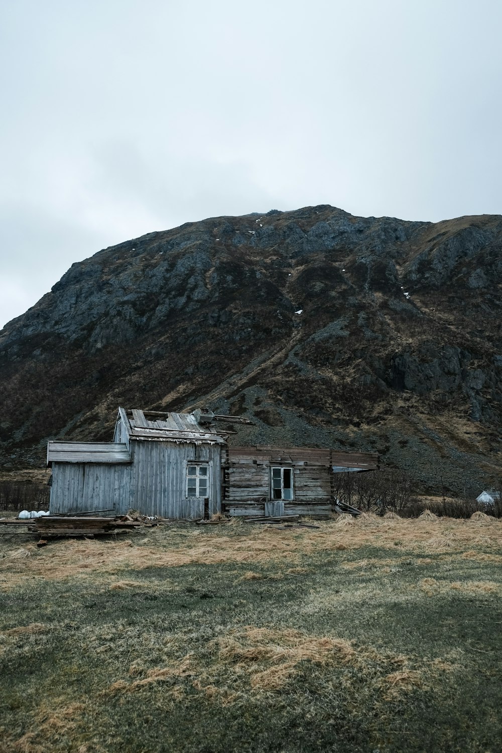 an old shack in a field with a mountain in the background