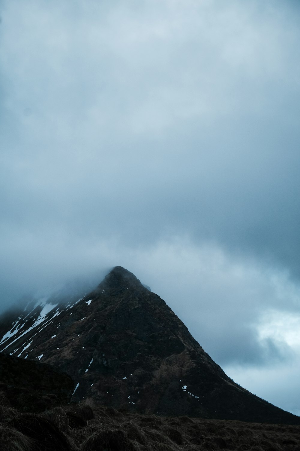 a very tall mountain covered in snow under a cloudy sky