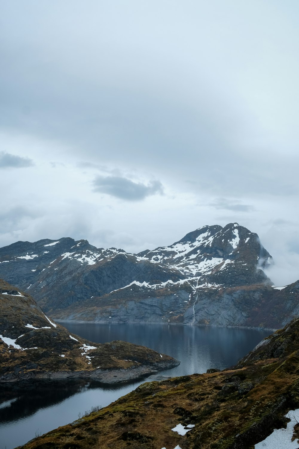 a mountain range with a body of water surrounded by snow