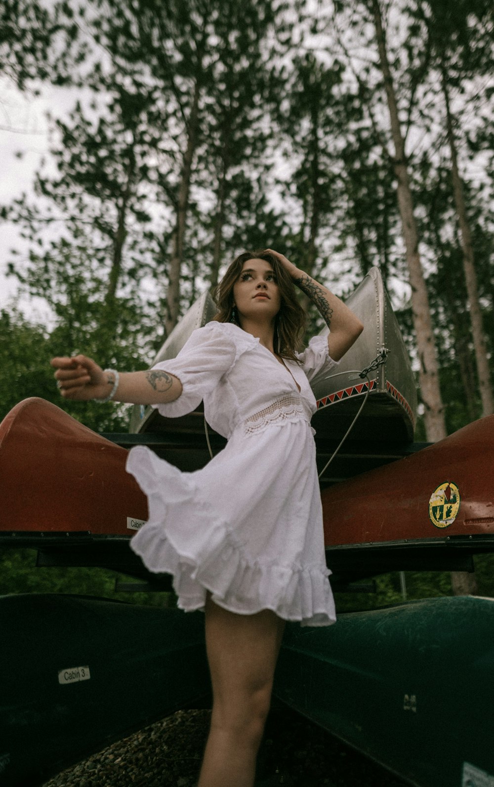 a woman in a white dress standing next to a canoe