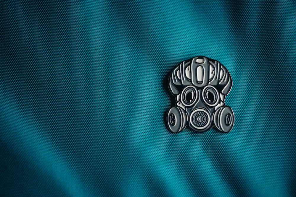 a close up of a blue fabric with a metal emblem on it