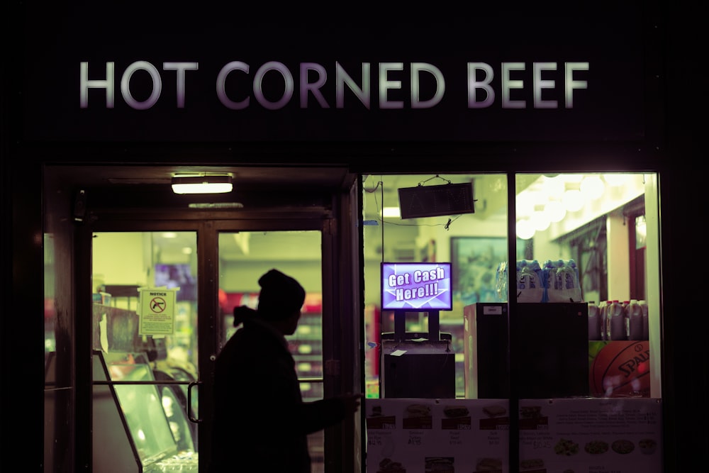a man standing outside of a hot corned beef restaurant