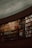 A large curved bookshelf filled with an array of colorful books. The shelves are stacked with volumes of varying sizes and colors, creating a visually rich tapestry. The setting is dimly lit, suggesting a quiet, introspective atmosphere. The architecture of the shelves suggests a library or study room environment.