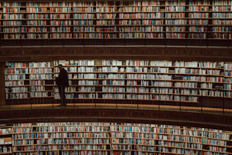 a man standing in front of a large amount of books