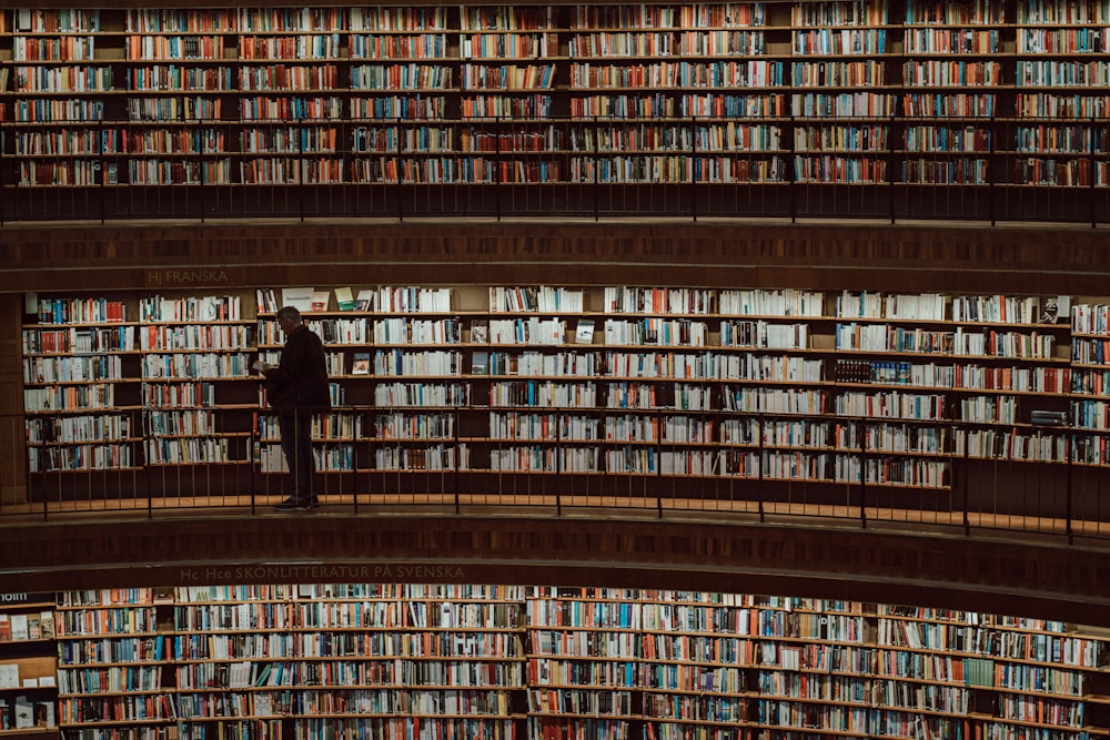 a man standing in front of a large amount of books