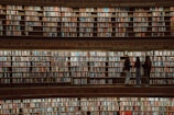 A group of people engaged in a discussion in a library filled with old books.