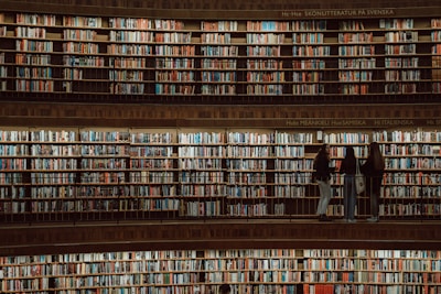 A group of people engaged in a discussion in a library filled with old books.