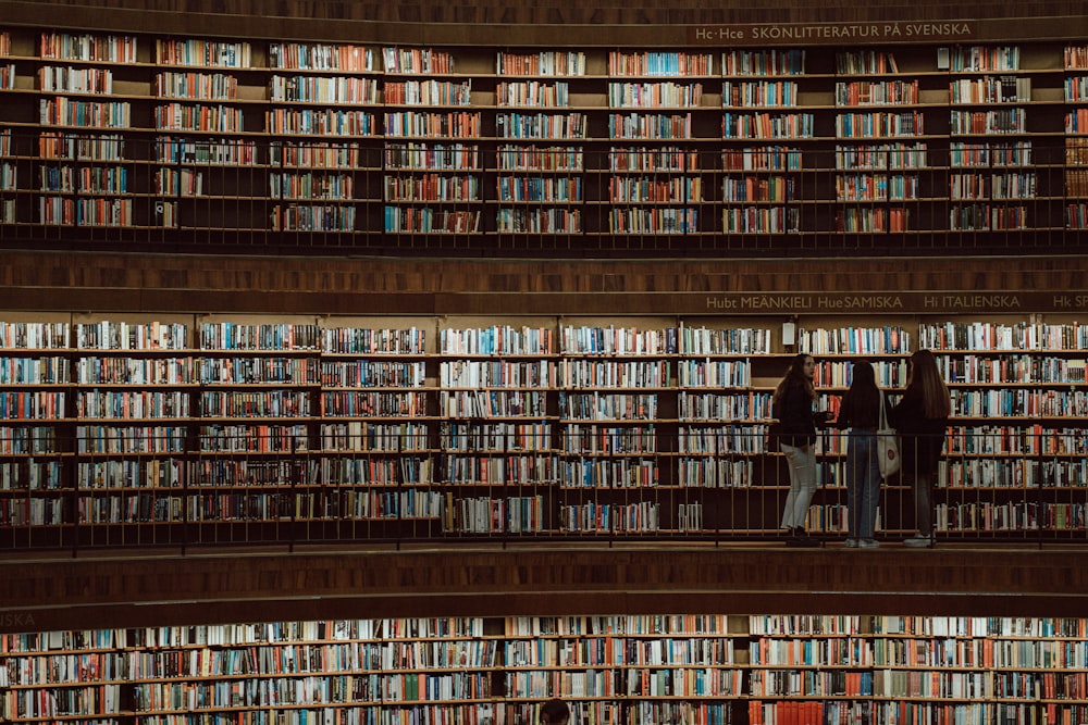 two people standing in front of a wall of books