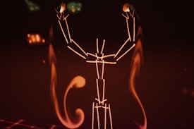 A digital illustration resembling a stylized human figure made of glowing lines against a dark background. The figure appears to be raising its arms, with abstract, flame-like shapes surrounding it.