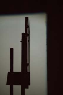 Abstract industrial machinery silhouette against a minimalist white background with thin grid overlays