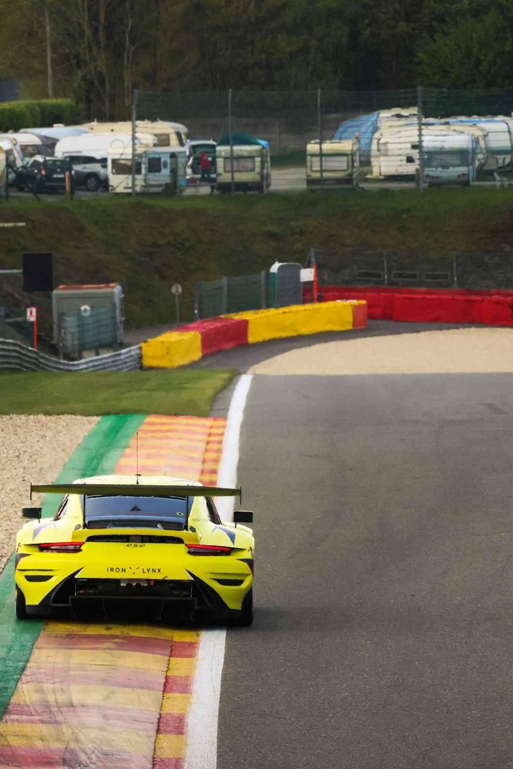 a yellow sports car driving on a race track