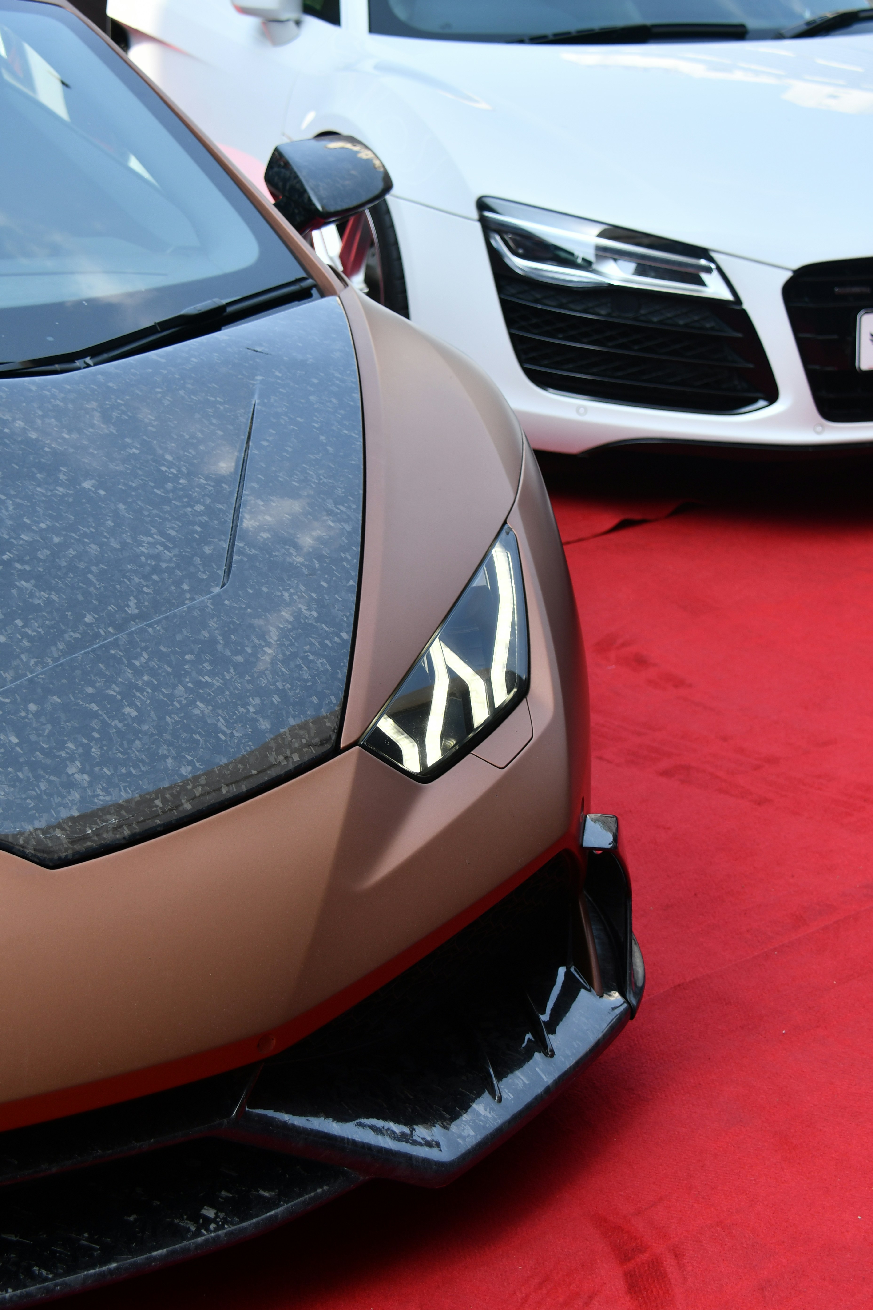 two cars parked next to each other on a red carpet