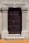 A robust wooden door framed by ornate stone pillars built into a beige stone facade. The door is dark brown and features a series of evenly spaced round metal studs and a central metallic handle.