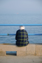 a person sitting on a ledge looking out at the water