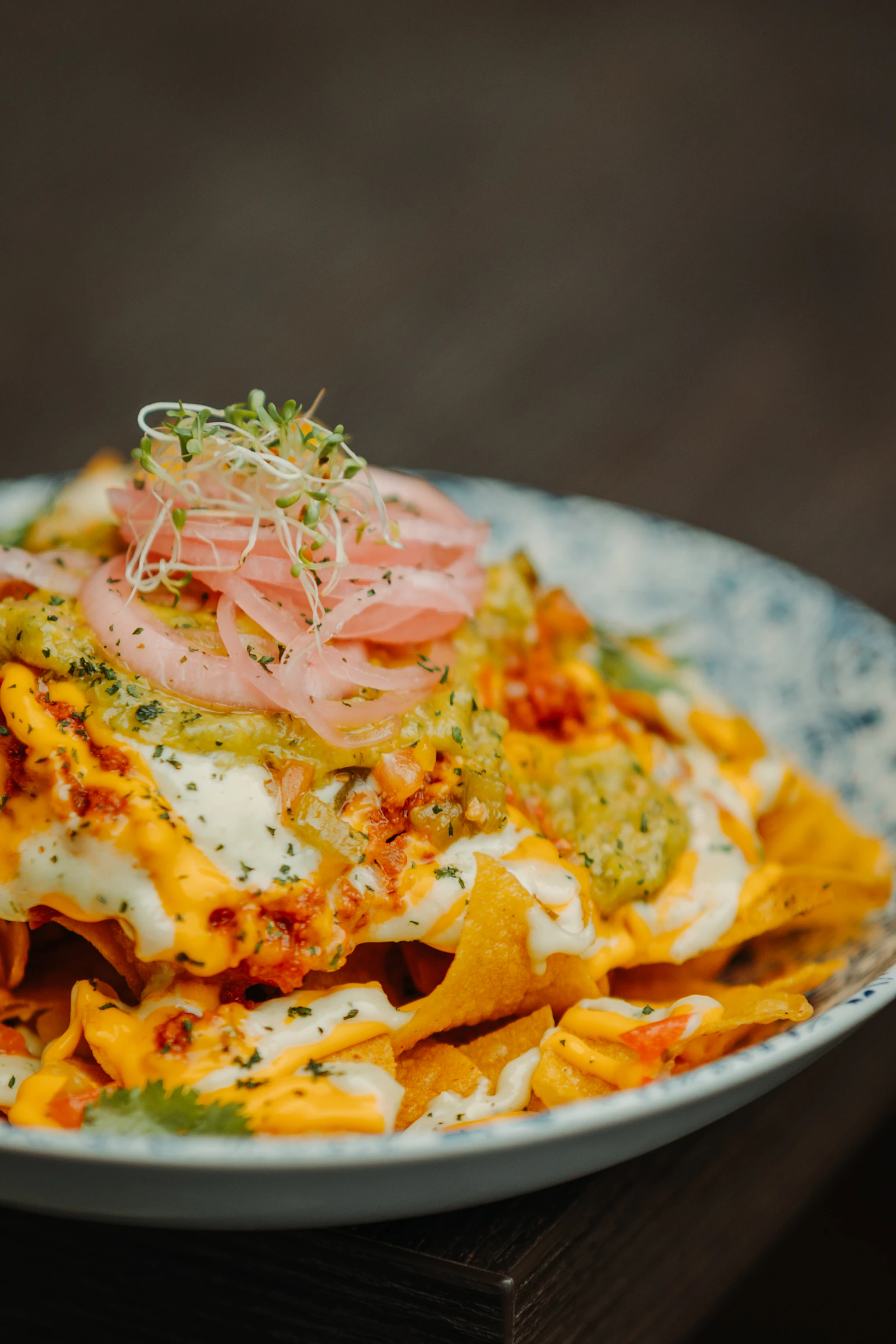 Loaded nachos with melted cheese, salsa verde, and pickled red onion