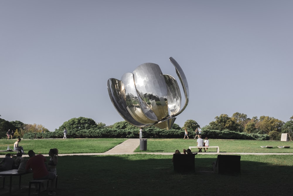 a large metal object sitting on top of a lush green field