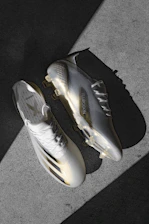 Close-up of sleek football cleats on a soft cream background highlighting their design.