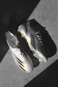 Close-up of sleek football cleats on a soft cream background highlighting their design details