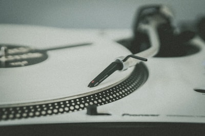 Close-up of a vintage Technics turntable tonearm and needle in a dimly lit workshop.