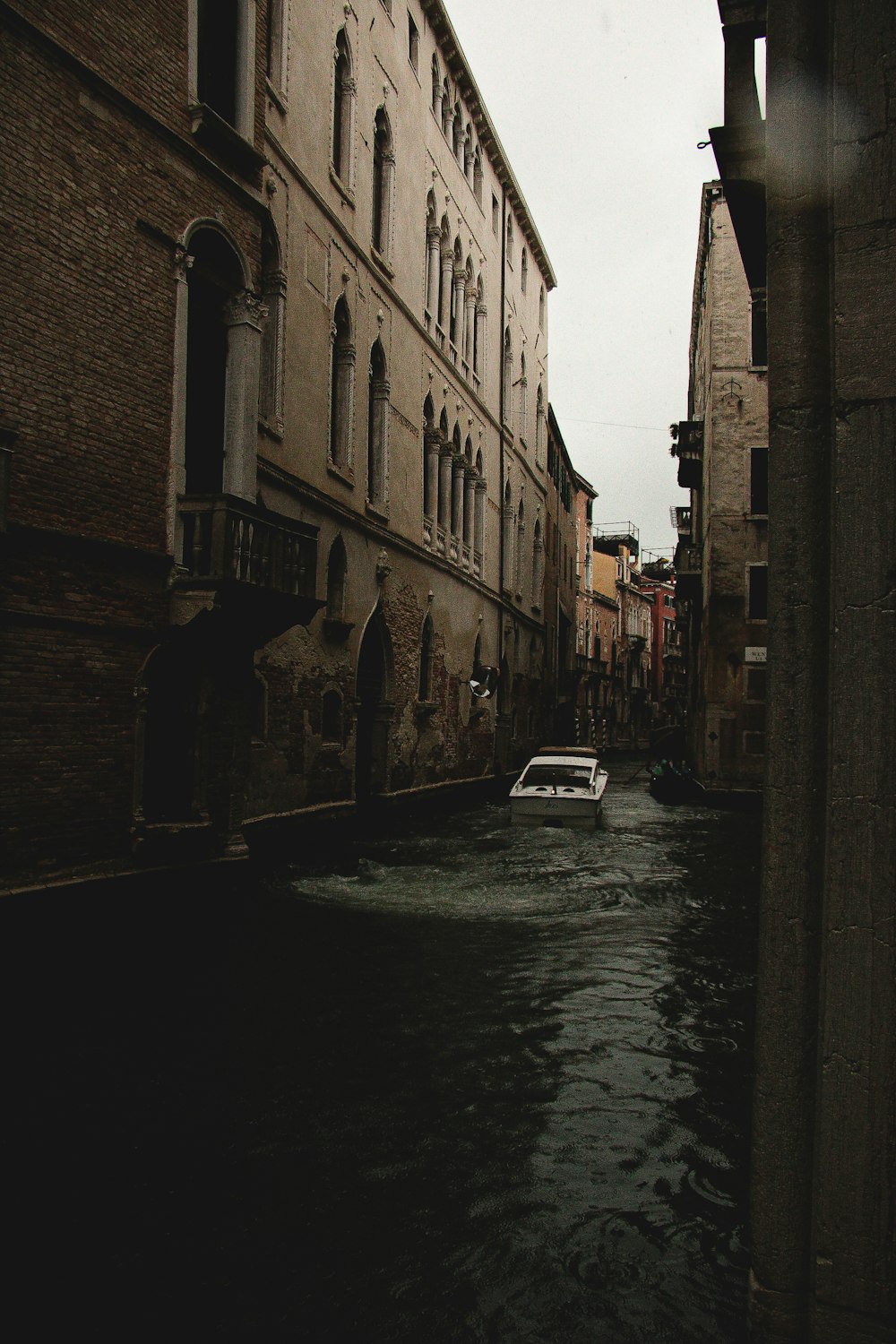 a white car driving down a street next to tall buildings