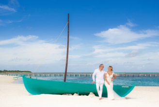 a man and a woman standing on a beach next to a boat