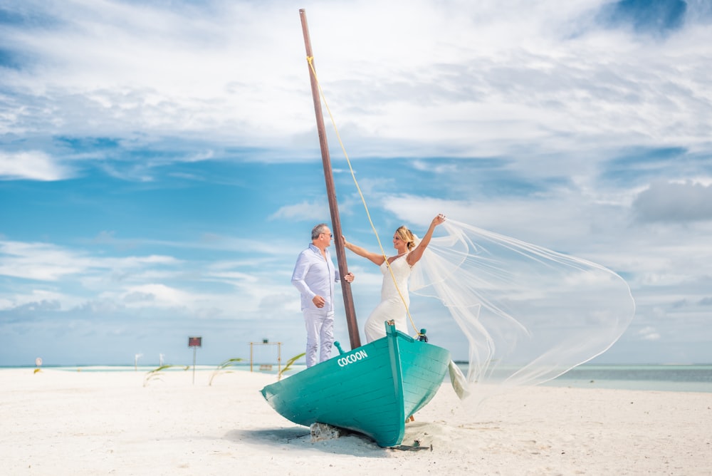 a bride and groom standing on a boat on the beach