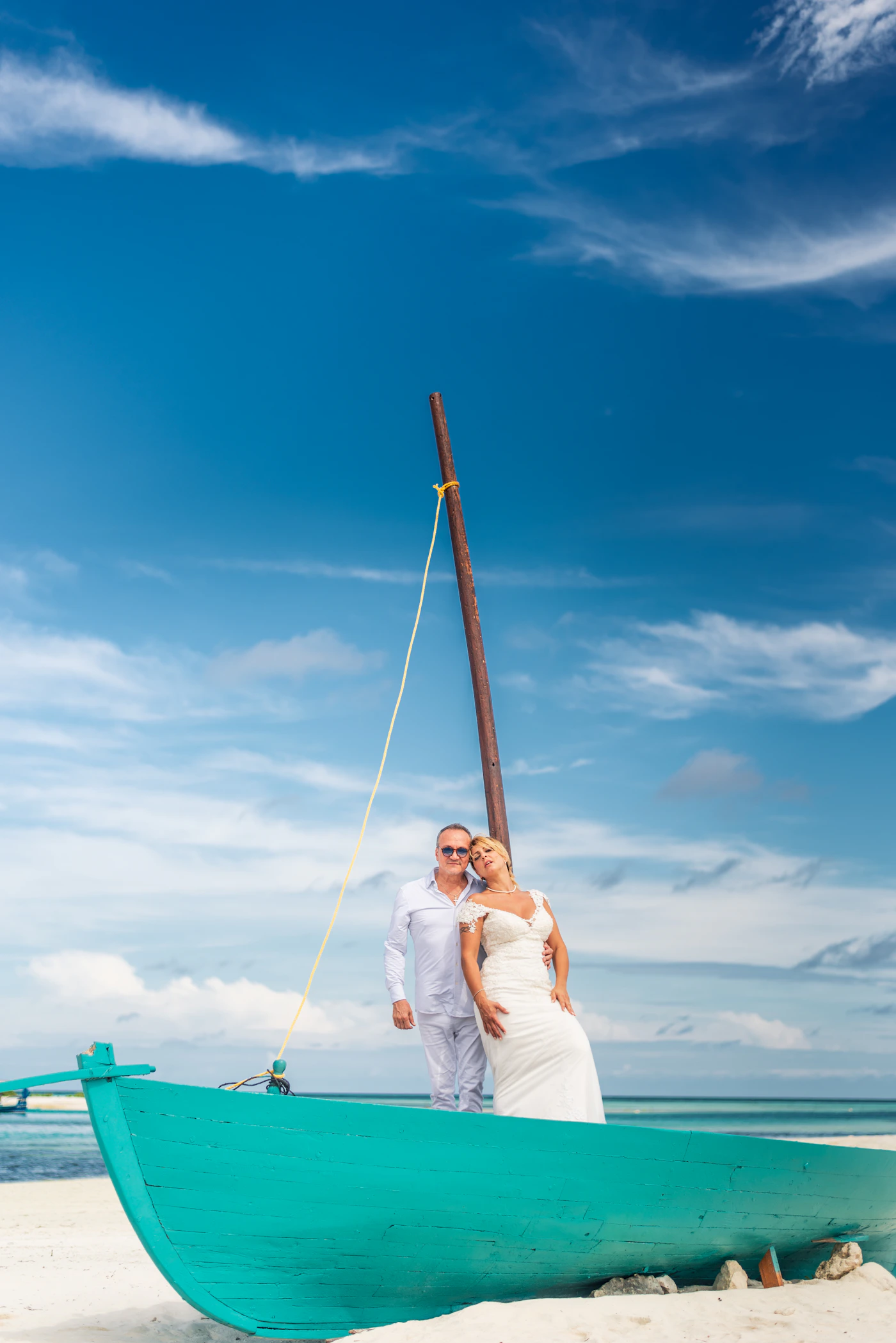 Bride and groom together on a boat by a tropical beach