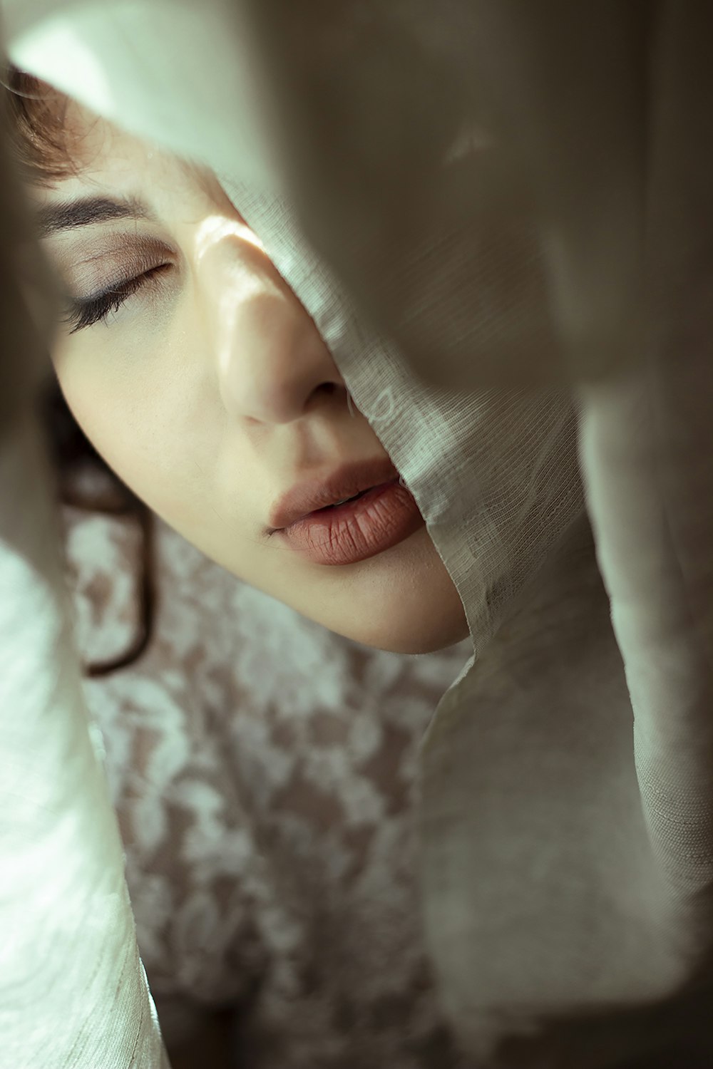 a woman with her eyes closed under a sheet