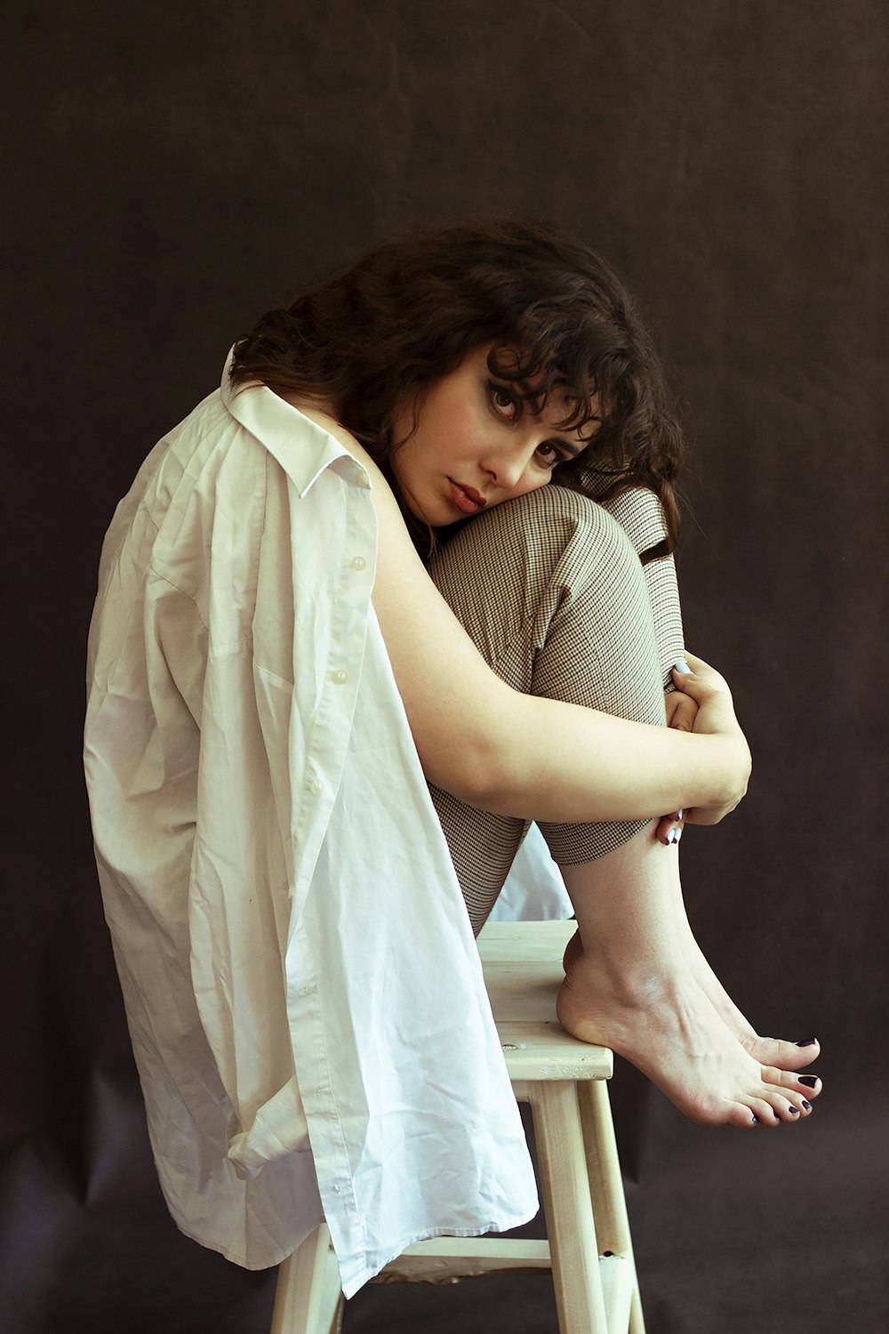 a woman sitting on top of a wooden stool