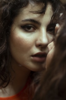 A close-up portrait of a person with curly hair and expressive eyes, capturing a reflective moment.
