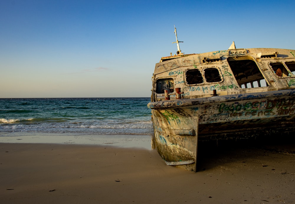 Un vieux bateau assis au sommet d’une plage de sable